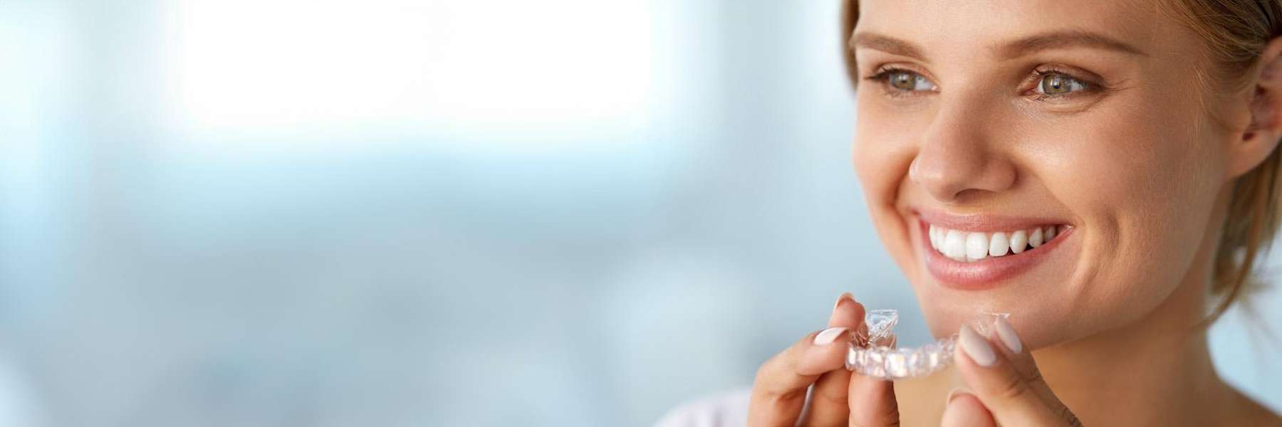 woman holding clear plastic aligner | dentist shady grove